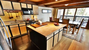 A kitchen with wooden cabinets, a microwave, stove, and a dining area with a table and chairs. - Near Trails! Big Deck! Easy Drive to Dining, Events, Activities, Lake (Silverthorne)