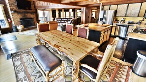 A rustic kitchen with a large wooden table and chairs, a brick fireplace, and modern appliances. - Near Trails! Big Deck! Easy Drive to Dining, Events, Activities, Lake (Silverthorne)