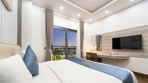 A hotel room with a bed, a desk, a TV, and a balcony with a view. - Winston Hotel Riverside (Ho Chi Minh City)