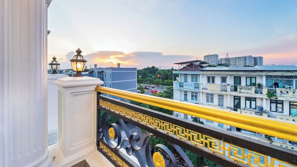 A balcony with a railing, a view of buildings, and a sunset in the background. - Winston Hotel Riverside (Ho Chi Minh City)