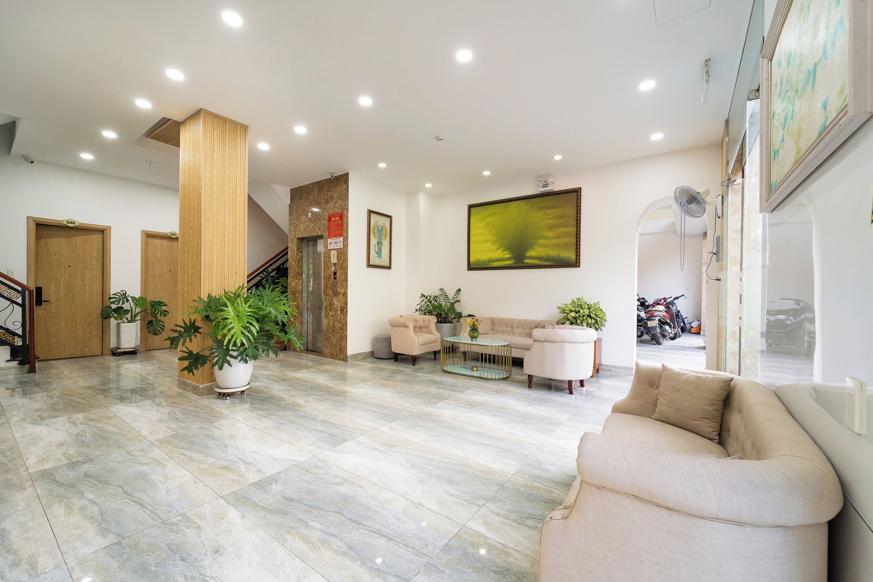 A spacious lobby with a marble floor, a sofa, a coffee table, and potted plants.