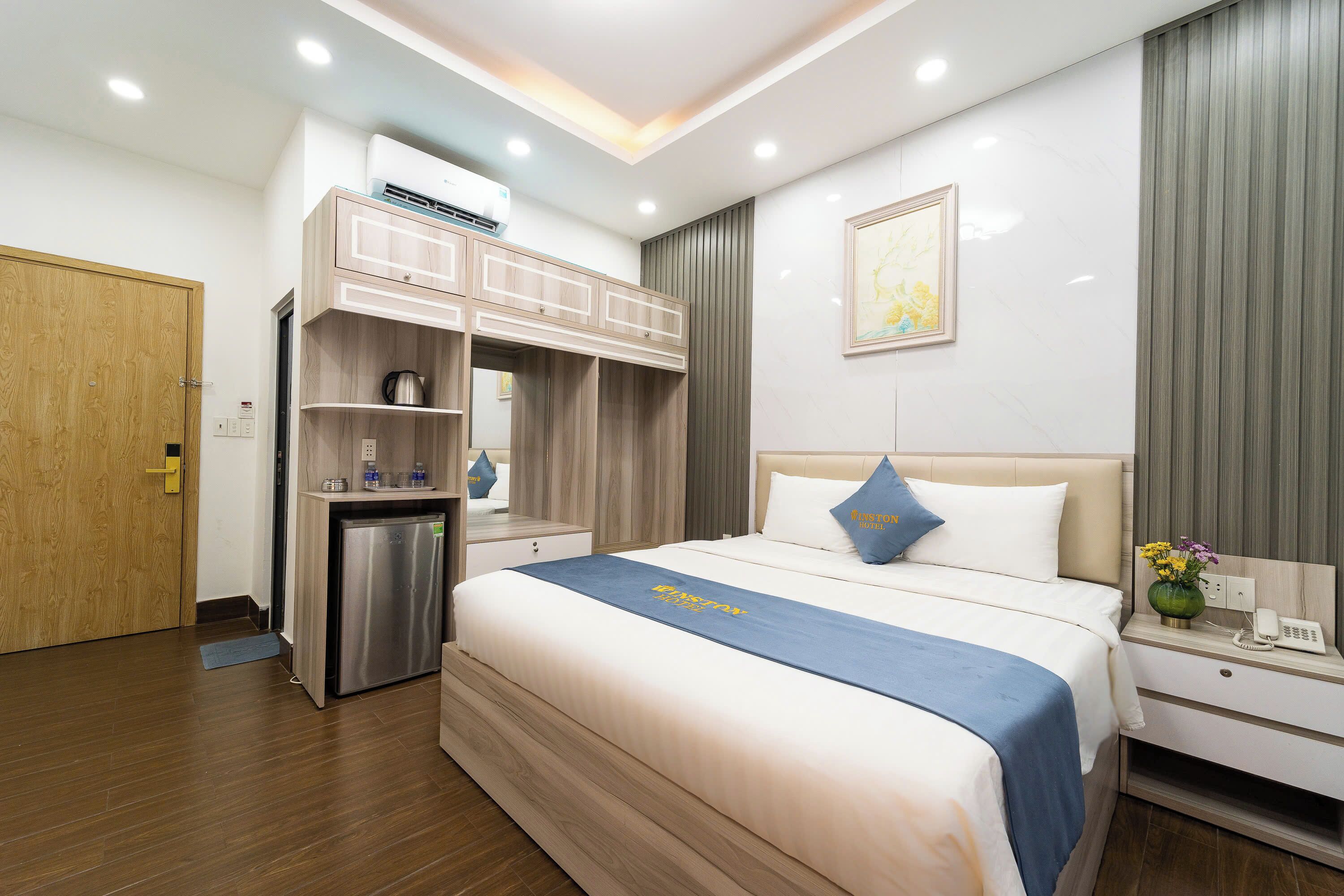A hotel room with a bed, a desk, a wardrobe, and a small kitchenette.