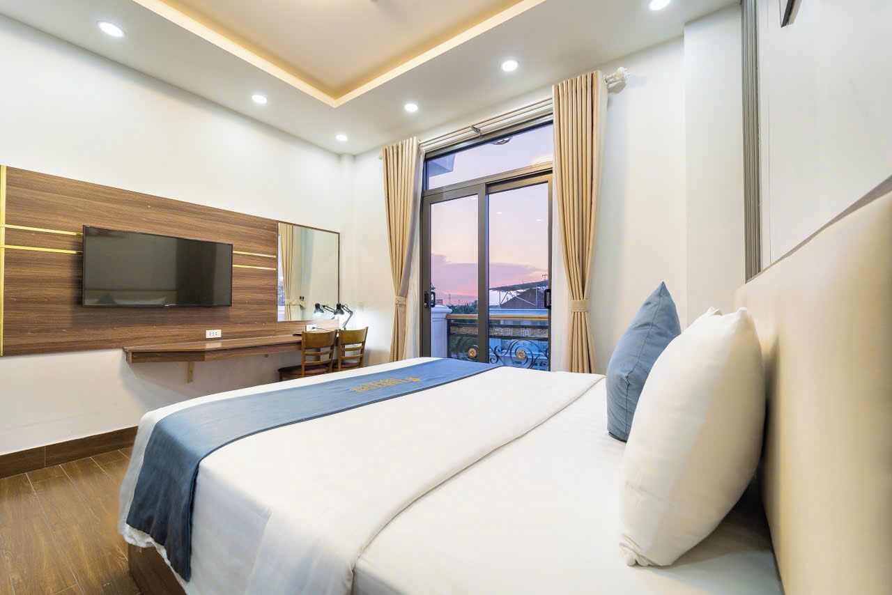 A hotel room with a bed, a desk, a TV, and a window with curtains.