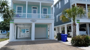 A two-story residential building with a balcony on the upper floor, a garage, and a paved driveway. - Ohana - Walk to beach in Surfside Beach (Surfside Beach)