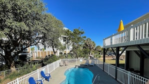 A swimming pool with a white deck, surrounded by a white fence. There are lounge chairs and a yellow umbrella. - Windjammer - Walk to Beach in Garden City Beach (Garden City)