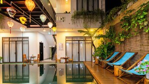 Una piscina interior con sillas de descanso, una escalera y faroles colgantes.