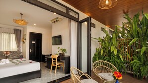 Una habitación de hotel moderna con cama, escritorio, silla y un pequeño balcón con plantas.