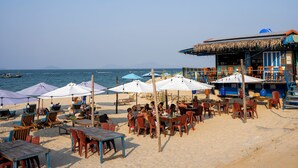 Un restaurante frente al mar con mesas al aire libre, sombrillas y vistas al océano.