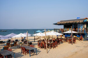 Un restaurante frente al mar con mesas al aire libre, sombrillas y vistas al océano.