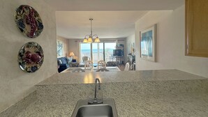 A kitchen with a granite countertop, a sink, and decorative plates on the wall. - Shores of Surfside I 103 - Oceanfront in Surfside Beach (Surfside Beach)