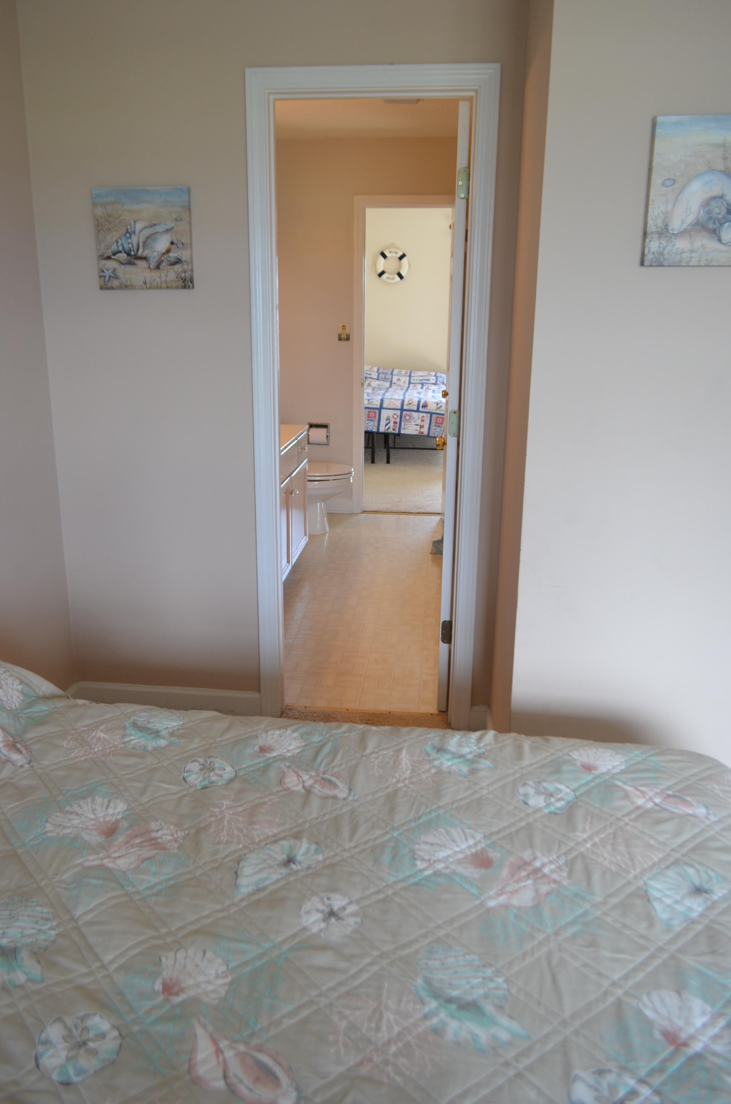 A bedroom with a bed, a door leading to a bathroom, and a hallway.