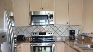 Una cocina con electrodomésticos de acero inoxidable, gabinetes de madera clara y un salpicadero de azulejos.