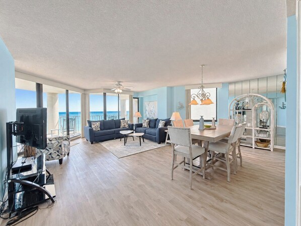 A spacious living area with a balcony, a dining table, and a television.