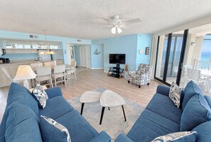 A spacious living area with a sofa set, a dining table, and a kitchen area with a TV.