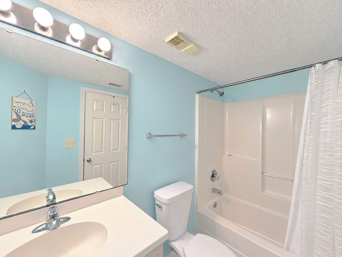 A bathroom with a sink, mirror, toilet, and shower.