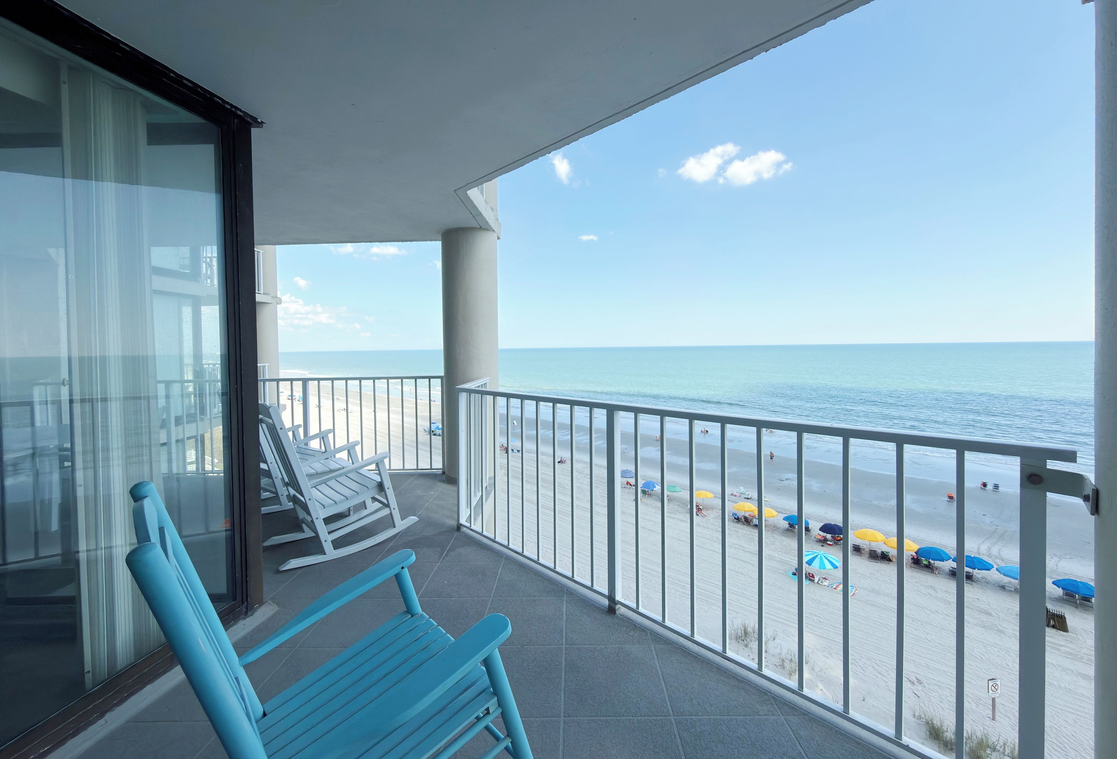 A balcony with a view of the beach and ocean.