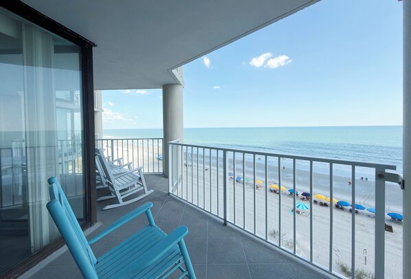 A balcony with a view of the beach and ocean.