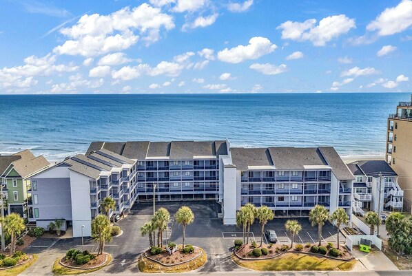 A coastal hotel with multiple floors, a parking area, and a view of the ocean. - Ocean Cove 309 - Oceanfront in Garden City Beach (Garden City Beach)