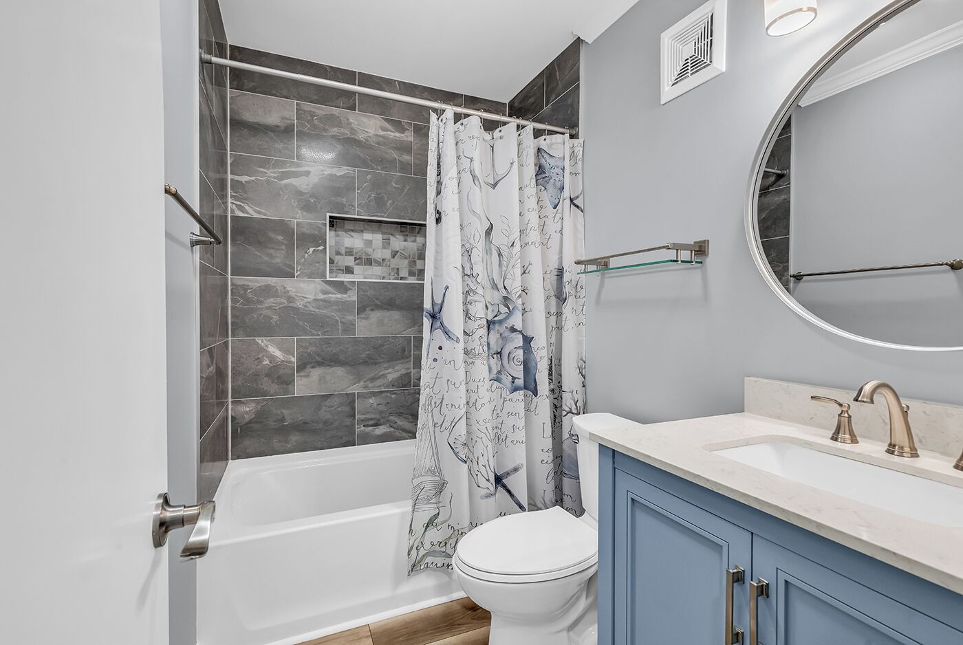 A bathroom with a bathtub, toilet, and vanity with a mirror.