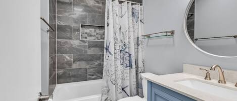 A bathroom with a bathtub, toilet, and vanity with a mirror.