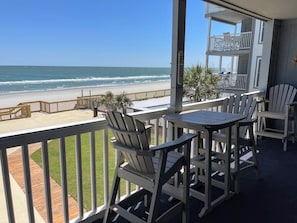 A balcony with Adirondack chairs and a table overlooking a beach. - Mariner's Watch 204 - Oceanfront in Garden City Beach (Garden City)