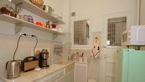 Una cocina con armarios blancos, cafetera, tostadora y microondas.
