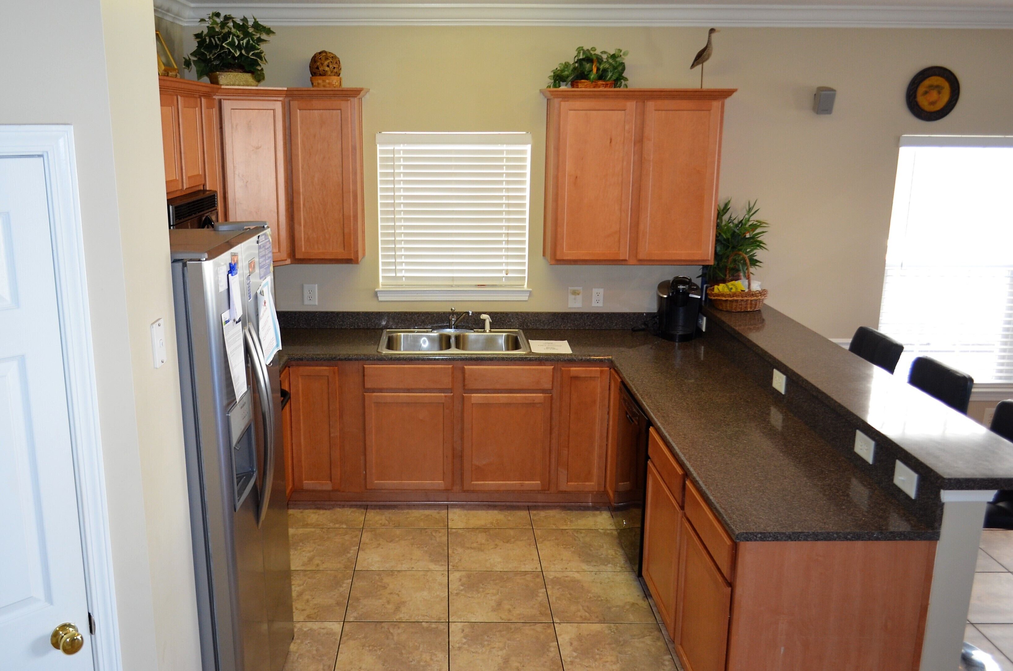 A kitchen with wooden cabinets, a stainless steel refrigerator, a sink, and a countertop.