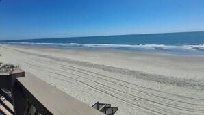Ein Strand mit einer Holzterrasse und freiem Blick auf den Ozean.
