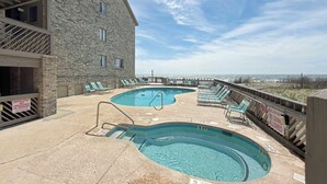 Ein Poolbereich mit zwei Pools, Liegestühlen und einer Holzterrasse.