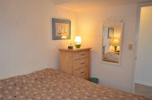 A bedroom with a bed, a dresser with drawers, a mirror, and a framed picture on the wall.