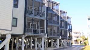A multi-story building with balconies, a car parked in front, and a clear sky. - Sea Oaks 310 - Oceanfront Complex (Oceanview Unit) in Garden City Beach (Garden City)