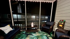 A balcony with wicker furniture, a patterned floor, and a decorative lantern. - Sea Oaks 310 - Oceanfront Complex (Oceanview Unit) in Garden City Beach (Garden City)