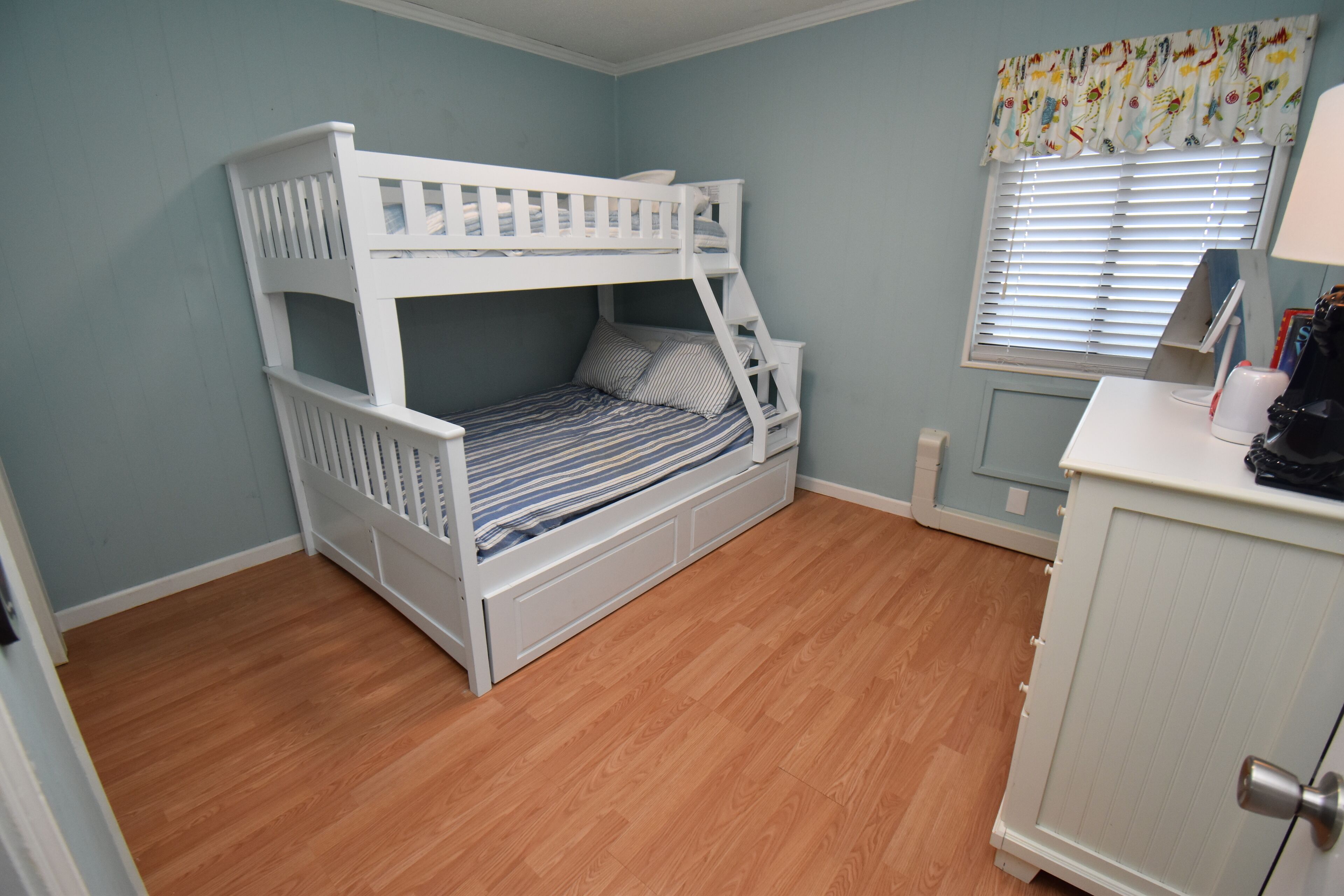 Una cama litera en una habitación con paredes azul claro y suelo de madera.