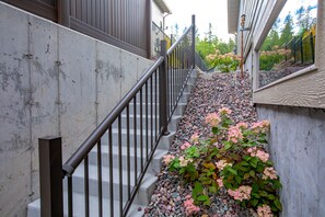 Stairs lead up to a building with a gravel path and flowering shrubs.