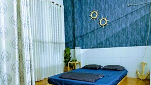 Ein Schlafzimmer mit einem hölzernen Bett, weißen Vorhängen, einer blauen Wand und einer kleinen Pflanze.