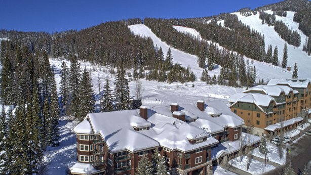 A snow-covered lodge with multiple buildings, surrounded by trees and a ski slope. - Some of the best direct ski access on the mountain!! 2 bedroom with beautiful valley views!! (Whitefish)
