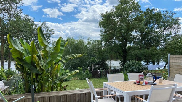 Een terras buiten met een houten tafel en stoelen, een koffiepot en een dienblad met kopjes.