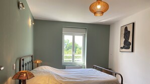 Een slaapkamer met een bed, nachtlampjes, een raam en een wanddecoratie.