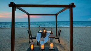 A beachside dining setup with a table, chairs, and lanterns under a wooden pergola, overlooking the ocean. - Paradise Trinco Beach  (TRINCOMALEE SRILANKA)