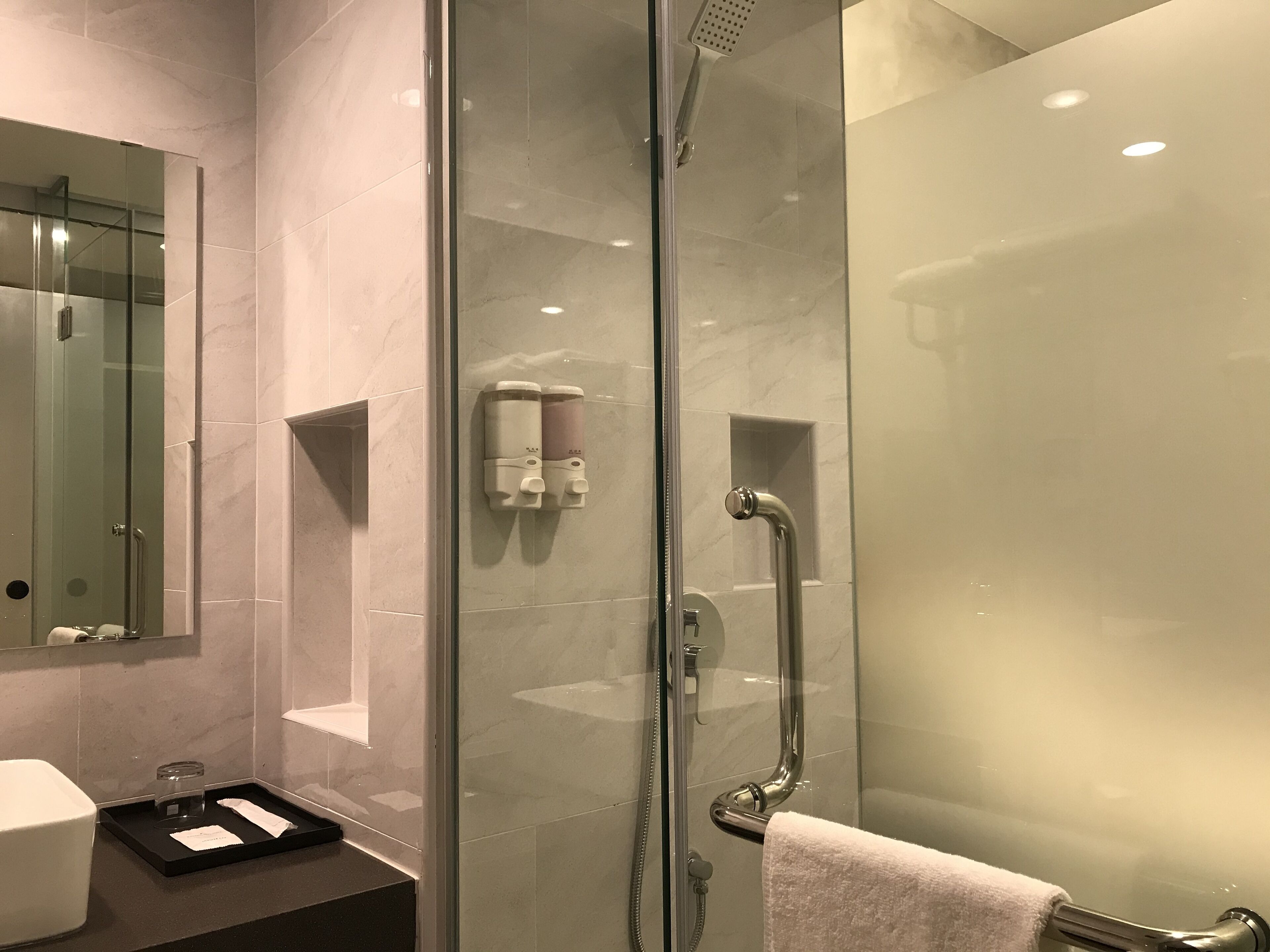 A modern bathroom with a glass-enclosed shower, a glass-enclosed mirror, and a towel rack.
