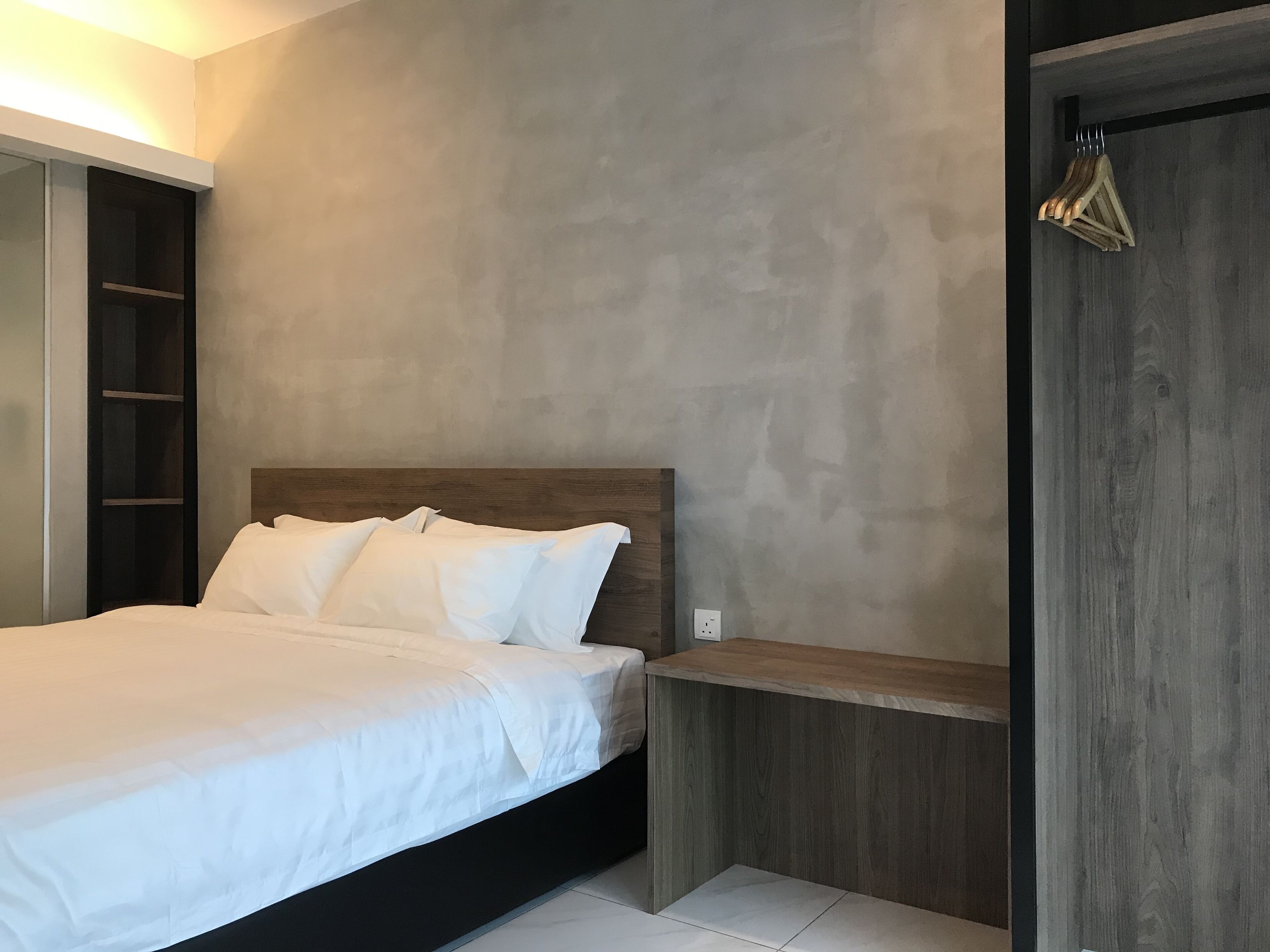 A modern bedroom with a bed, a wooden headboard, a built-in bench, and a wardrobe with a mirror.