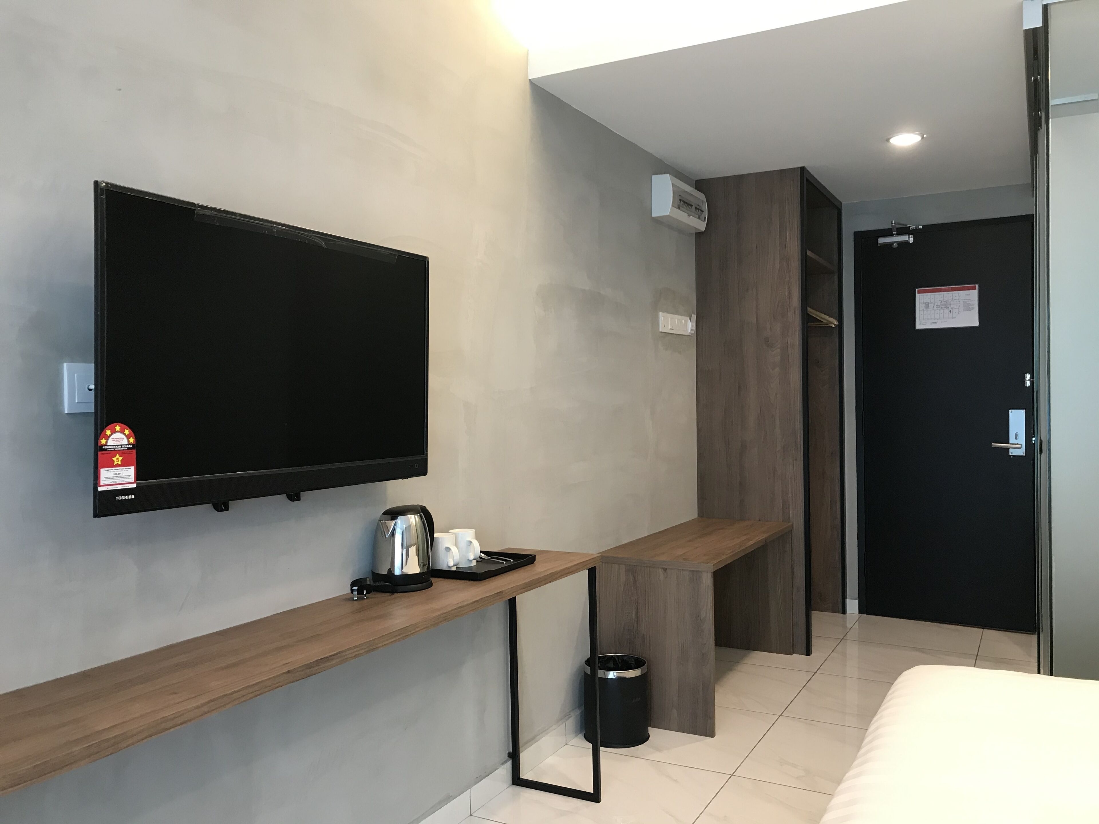 A modern hotel room with a flat-screen TV, a coffee maker, and a trash bin.