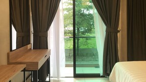 Un dormitorio con un ventanal grande, un escritorio de madera y una cama.
