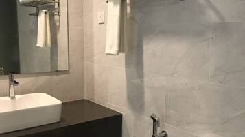 A modern bathroom with a white sink, a toilet, and a towel rack with folded towels.