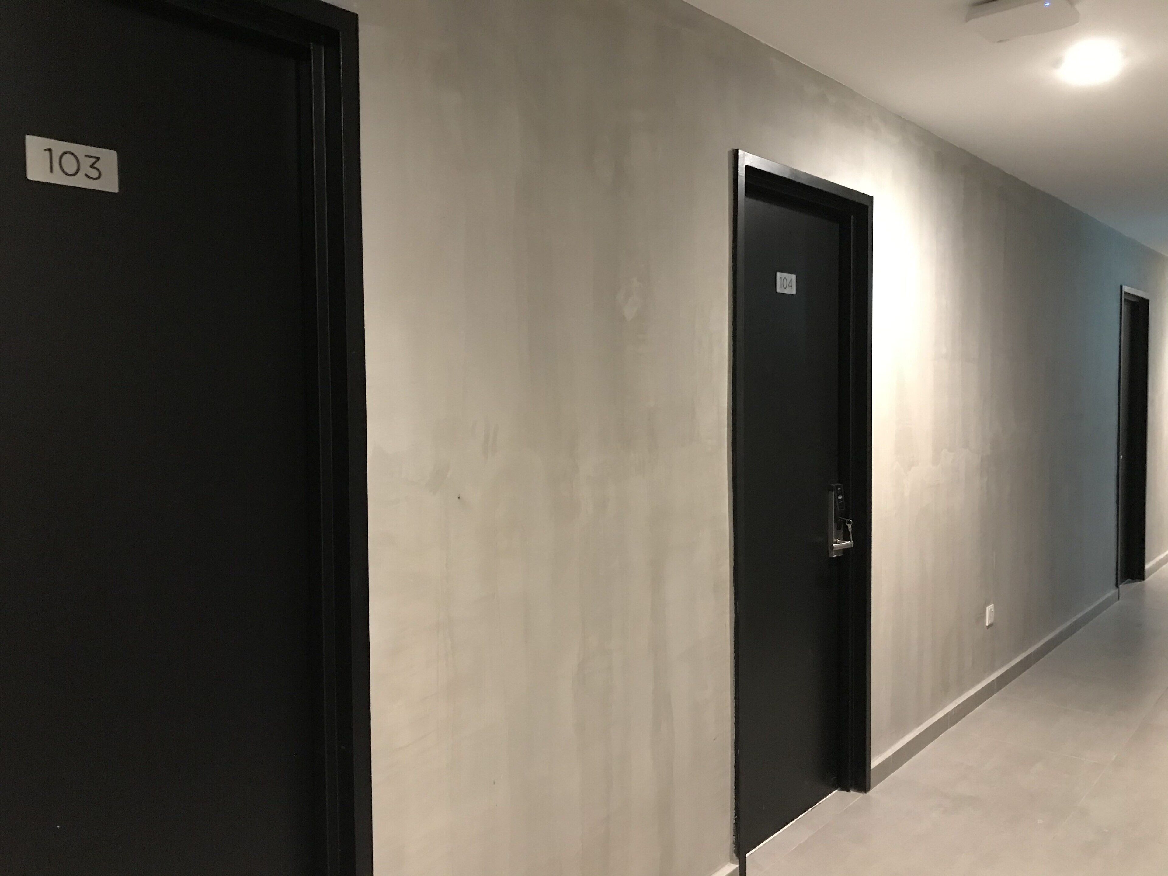 A hallway with doors numbered 103 and 104, light-colored walls, and a tiled floor.