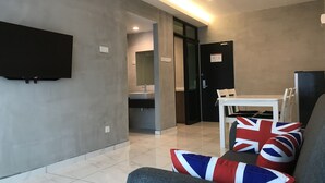 A modern living room with a flat-screen TV, a dining table with chairs, and a sofa with British flag cushions.