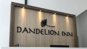 A wooden reception desk with the text "Dandelion Inn" and a logo above it.