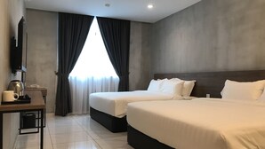 Habitación de hotel con dos camas, un escritorio con teléfono y cafetera, y un ventanal con cortinas.