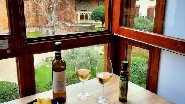 Una taula amb una ampolla de vi, dues copes, una ampolla d'oli d'oliva i un plat de formatge, carn i olives.