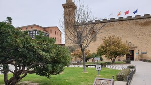 Un pati amb una paret de pedra, una estàtua de lleó i un pal amb diverses banderes.